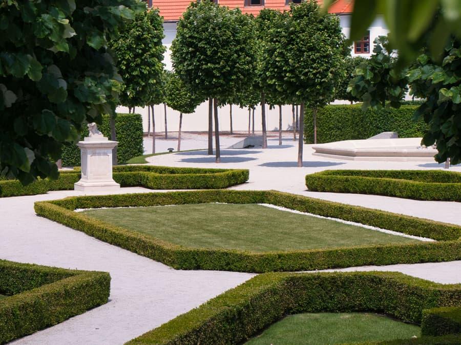 Neatly trimmed hedges and clean lawn panels in front of a building